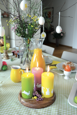 Frühlingsfrisch und liebevoll mit einem Kaninchen verziert: die neuen eika Stumpenkerzen. Foto: Bolsius Deutschland GmbH/akz-o