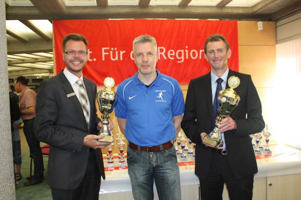 Die beiden neuen Pokale für die Gemeindemeister über zehn Kilometer zeigten Peter Ueberberg (l.), Regionaldirektor der Kreissparkasse Köln, und Jens Langner (r.), Geschäftsführer der BEW, im Beisein des Lindlar-läuft-Vorsitzenden Carsten Ommer (M.) - Quelle: Andrea Knitter/Lindlar läuft.