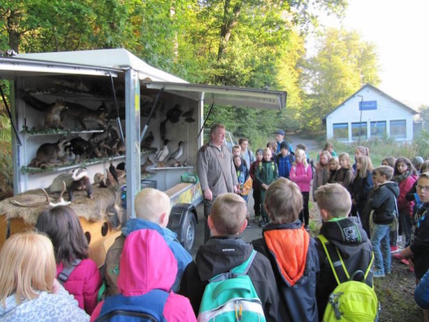Herr Ommer erklärt vor dem Wagen der "rollenden Waldschule" beiden Klassen den Ablauf des Tages - Foto: Gesamtschule Marienheide.