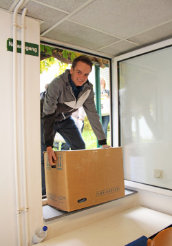 Helfer tragen Kisten mit Kleidung in die Einrichtung (Foto: OBK).