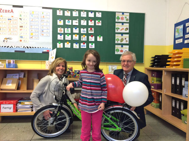 Gewinnerin Paula (vorne) freute sich sehr über ihren Fahrrad-Gewinn. Übergeben wurde ihr der Preis von Helmut Wagner, Regionaldirektor der Kreissparkasse Köln (rechts außen) und Helga Kohlgrüber, Schulleiterin (Foto: Kreissparkasse Köln).