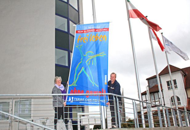 Die Gleichstellungsbeauftragte des Oberbergischen Kreises Sabine Steller und Kreismitarbeiter Jörg Braun hissen die blaue Fahne vor dem Kreishaus (Foto: OBK).