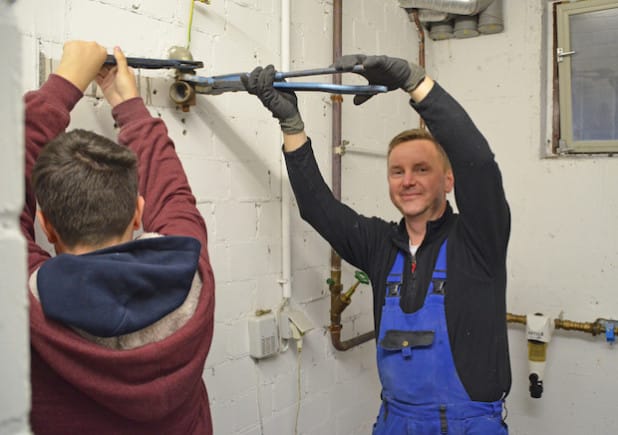 Thomas Meyrahn (Ziess Sanitär- und Heizungstechnik, r.) wird bei der Arbeit von Tagespraktikant Timon. (Foto: OBK)