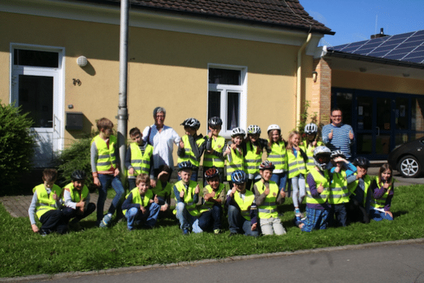 Brunhild Königs und Iara Behs-Dietsche überreichten dem Schulleiter Edgar Prinz und den Viertklässlern die Warnwesten für die nächsten Prüflinge. Die Freude der Kids ist nicht zu übersehen. Cool fanden sie es auch, dass da ein Löwe auf der Vorderseite zu sehen ist, nämlich das aufgedruckte Lions Logo. (Quelle: Renate Wigger)